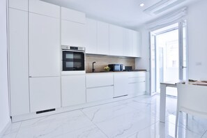 Een moderne keuken met witte kasten, een inbouwoven en een groot raam.
