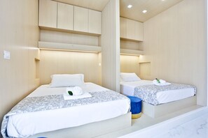 Een hotelkamer met twee bedden, een blauwe kruk en een spiegel.