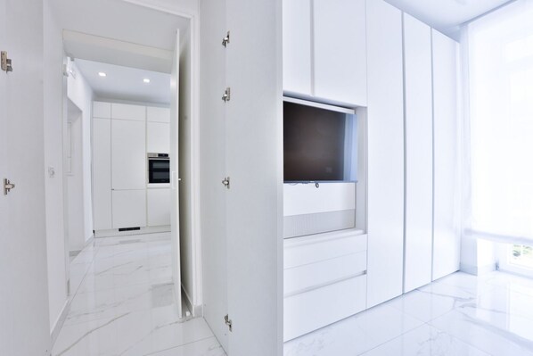 A modern interior with a kitchen area, a hallway, and a living space with a TV mounted on the wall.
