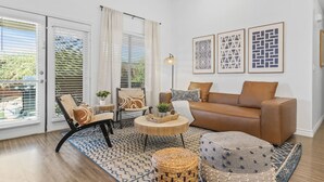 A living room with a brown sofa, two armchairs, a coffee table, and a patterned rug.