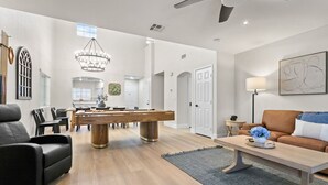 A spacious living area with a pool table, a sofa, and a dining area. - Spacious 5 BD Home w/Theater, Billiard, and More! (North Las Vegas)