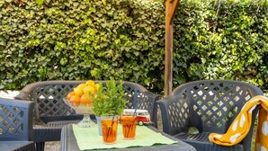 Een terras met een tafel voor twee personen, een fruitschaal en een bloempot.