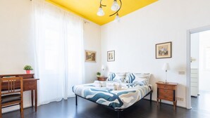 Een slaapkamer met een bed, nachtkastjes, een bureau en een stoel.