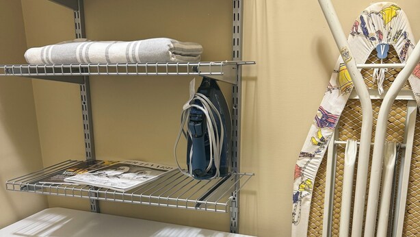 A bunk bed with a top bunk having a quilted blanket, a desk with a chair, and an ironing board with a patterned cover. - Beautiful Queen Suite near Castle, City & Beach (Victoria)