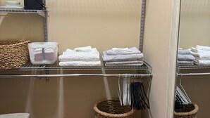 A bathroom with a wooden floor, a mirror, a shelf with towels, a basket, and a fan. - Beautiful Queen Suite near Castle, City & Beach (Victoria)