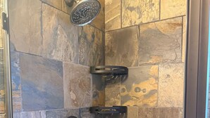 A shower area with stone tiles and a handheld showerhead. - Beautiful Queen Suite near Castle, City & Beach (Victoria)