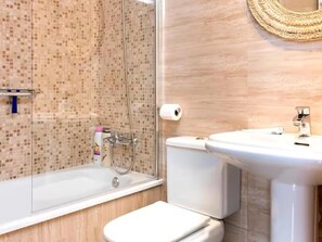 A bathroom with a glass-enclosed shower, a toilet, and a sink.