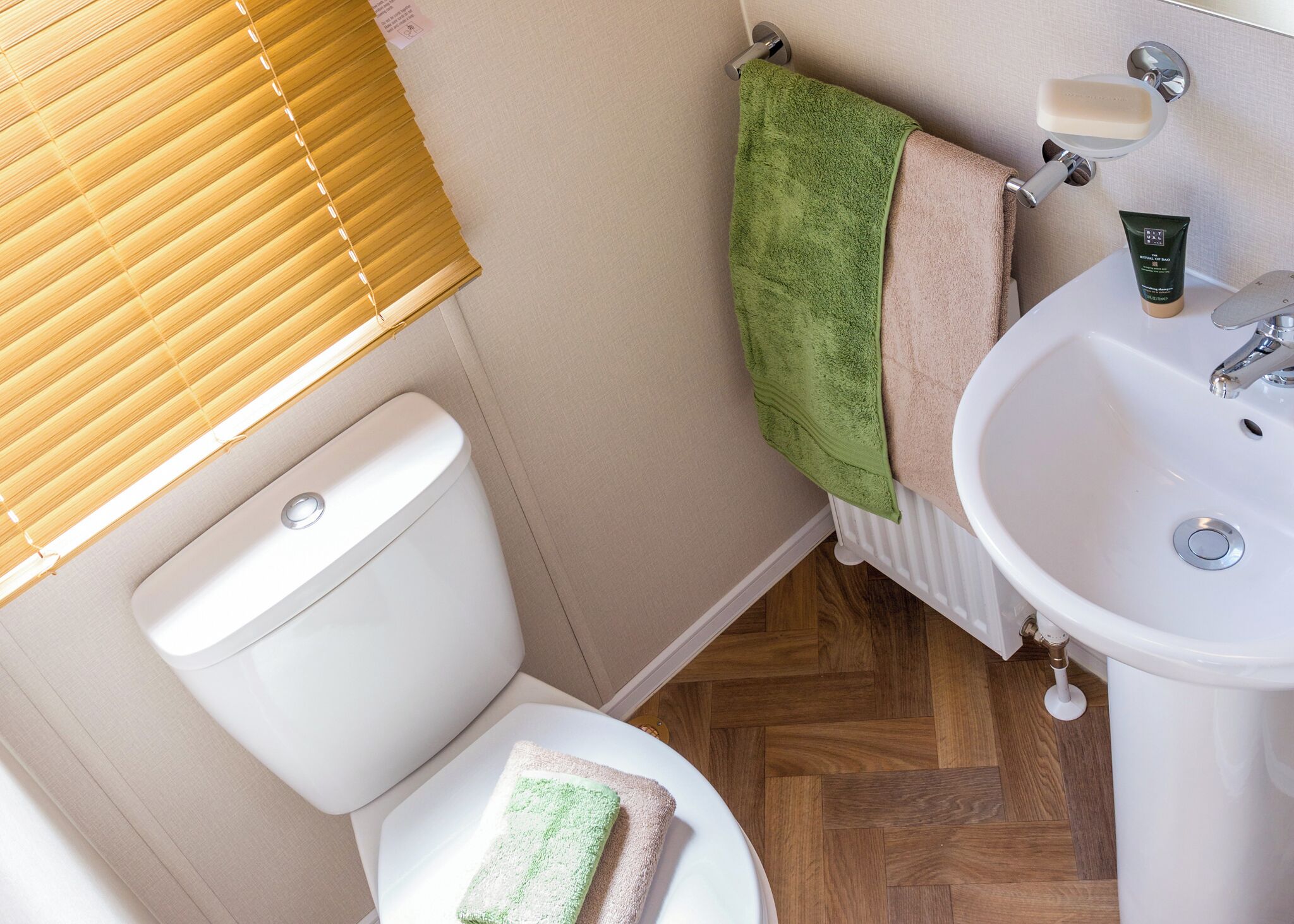 Ein Badezimmer mit Toilette, Waschbecken, Handtuchhalter und einer Handseifenflasche.