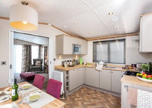 A modern kitchen with a dining area, a built-in oven, and a window with blinds. - 2 bedroom accommodation in Nr Kintore (Nr Kintore)