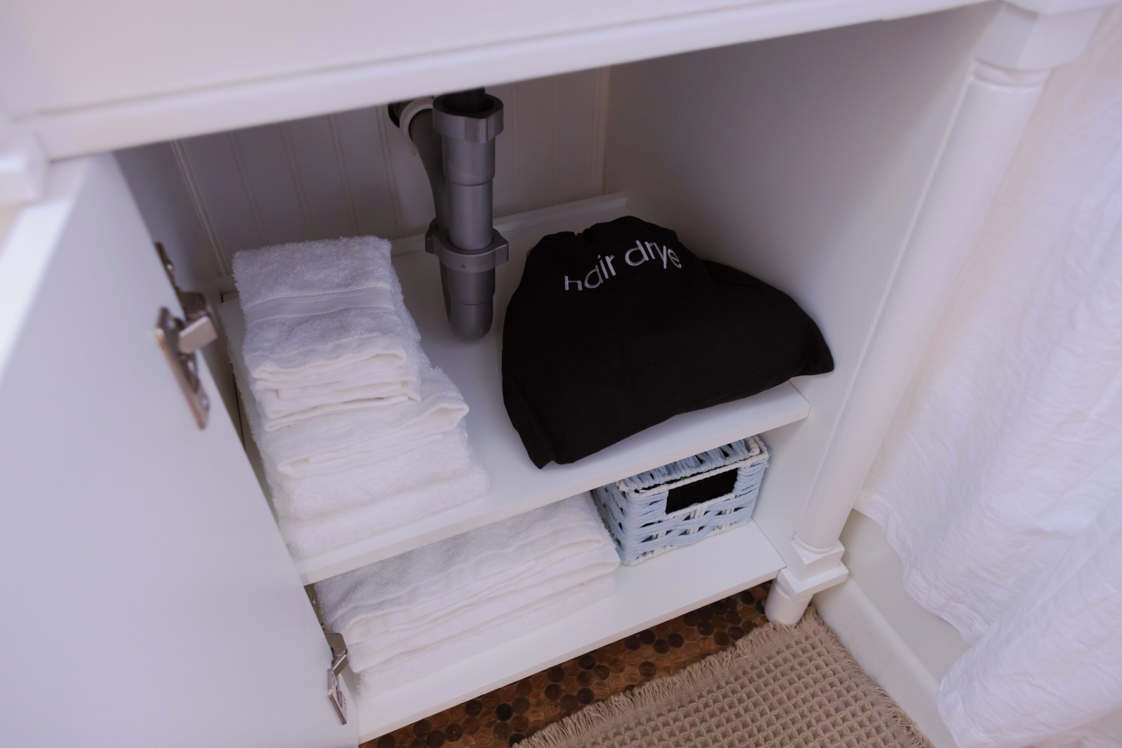 Casa de banho com toucador branco, secador de cabelo e toalhas dobradas com cuidado.