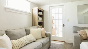 Una sala de estar con dos sofás, un aparador de madera y una puerta que da al exterior.