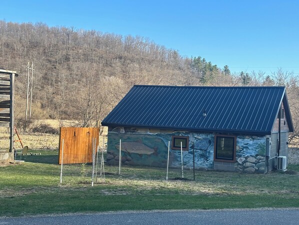 Un bâtiment rustique avec un toit en métal, un mur en pierre et une fresque murale.