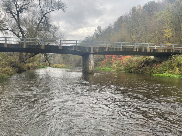 Un puente sobre un río con una ladera boscosa al fondo.