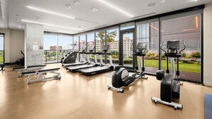 Ein modernes Fitnessstudio mit Laufbändern, Krafttrainingsgeräten und einem großen Fenster mit Blick auf die Stadt.