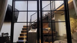 A modern interior with a wooden ceiling, a staircase, a kitchen area, and a seating area with a sofa and a coffee table. - Sienna House Kerobokan (Kerobokan)