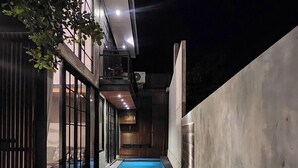 A modern outdoor pool area with a clear view of the pool, surrounded by a concrete wall and a glass fence. - Sienna House Kerobokan (Kerobokan)