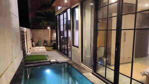 A modern building with a swimming pool, large windows, and a well-lit interior. - Sienna House Kerobokan (Kerobokan)