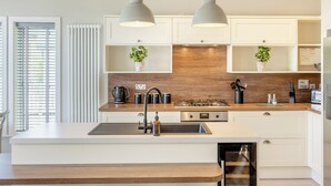 A modern kitchen with white cabinetry, a wooden countertop, a built-in stove, and pendant lighting. - Luxury new Lakeside lodge with spacious and open plan living and kitchen area. (Woodhall Spa)