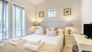 A bedroom with a bed, bedside tables, lamps, a desk, and a television. - Luxury new Lakeside lodge with spacious and open plan living and kitchen area. (Woodhall Spa)