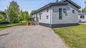A two-story building with a gravel driveway, a wooden bench, and a small brick structure. - Luxury new Lakeside lodge with spacious and open plan living and kitchen area. (Woodhall Spa)