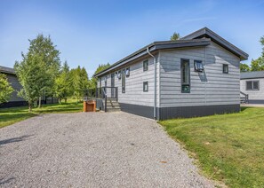 Een gebouw met twee verdiepingen, een grindpad, een houten bankje en een klein bakstenen bijgebouw.