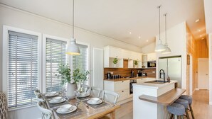 Een moderne keuken met witte kasten, een centraal eiland en hanglampen.