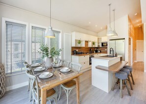 Een moderne keuken met witte kasten, een centraal eiland en hanglampen.