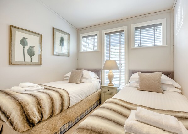A double room with two beds, a bedside table with a lamp, and artwork on the wall.