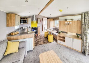 A compact kitchen with a central island, a dining area with a table and chairs, and a cozy seating area with cushions.