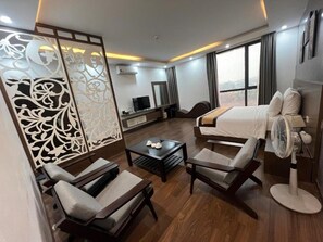 A modern hotel room with a bed, two armchairs, a coffee table, a TV, and a large window. - Kim Thanh Hotel, Tam Duong - Near The Golf Panaroma, Tam Dao (Tam Duong)