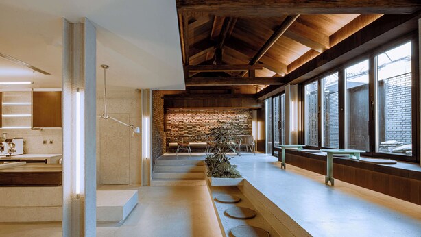 Un intérieur moderne avec un long comptoir, de grandes fenêtres et un mur en briques.
