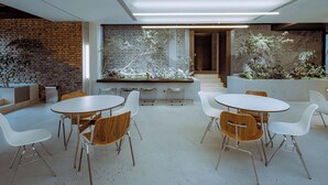 Un espace intérieur moderne avec un mur en briques, des tables et des chaises blanches.
