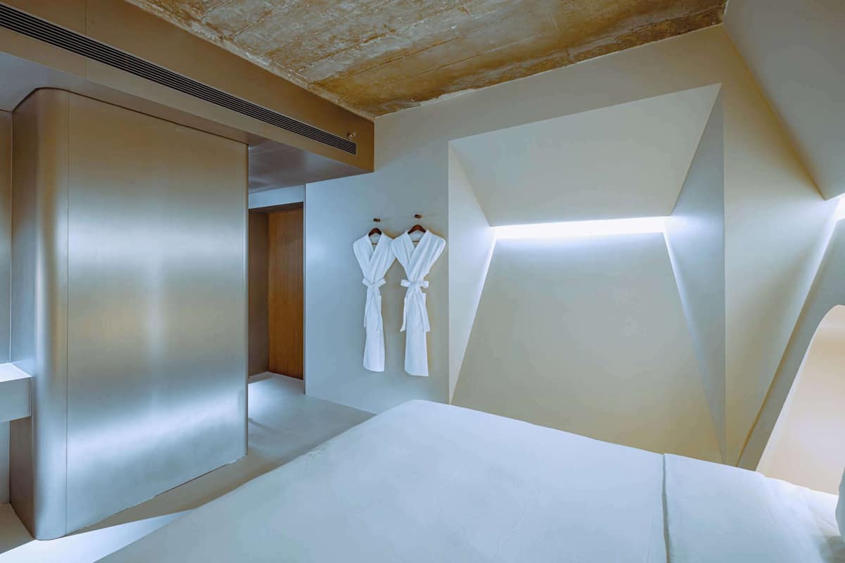 Una habitación de hotel moderna con una cama grande, un armario empotrado y zona de ducha.
