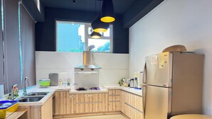 Une cuisine moderne avec des meubles en bois, un réfrigérateur en acier inoxydable et une fenêtre qui laisse entrer la lumière naturelle.