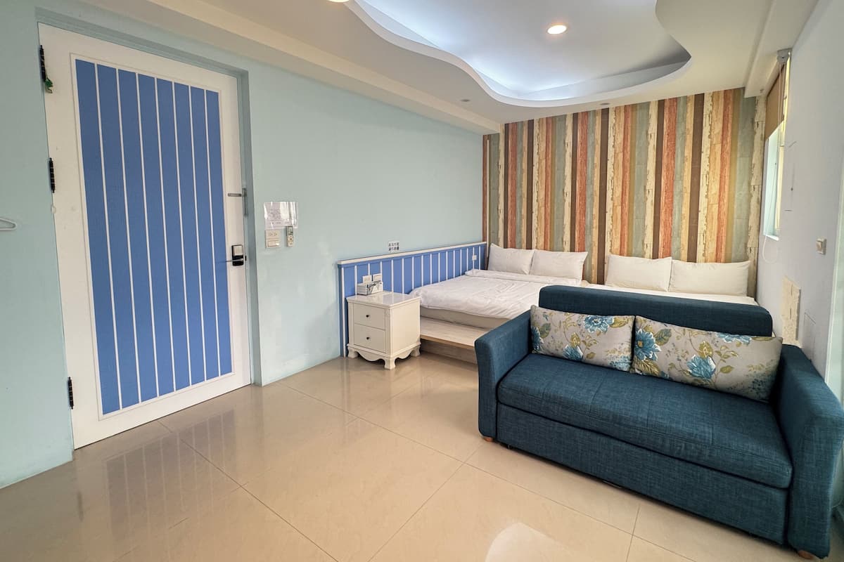 A modern bedroom with a bed, a blue sofa, and a striped wall.