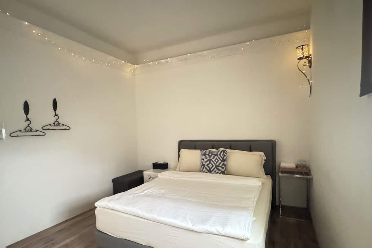 A neatly arranged bedroom with a bed, bedside tables, and decorative wall lights.