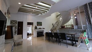 Un vaste espace de vie agrémenté d’un escalier moderne, d’une cheminée et d’un ensemble de salle à manger.