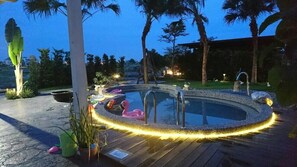 A hot tub surrounded by a wooden deck, palm trees, and decorative flamingos. - Win-win Villa (Dongshan)