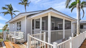 A coastal house with a covered porch, white railings, and a wooden deck.