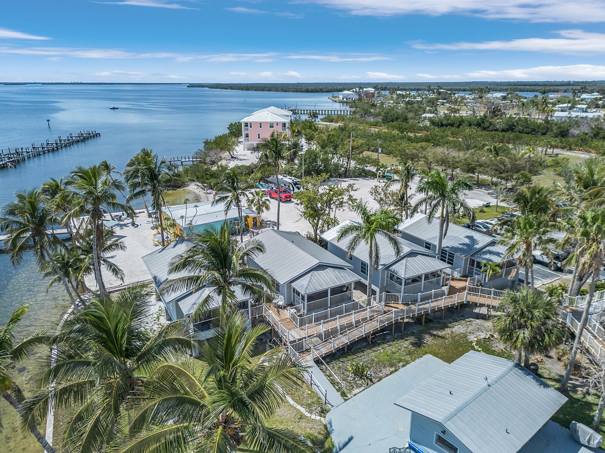 A coastal property with multiple buildings, a dock, and a beach area with palm trees.