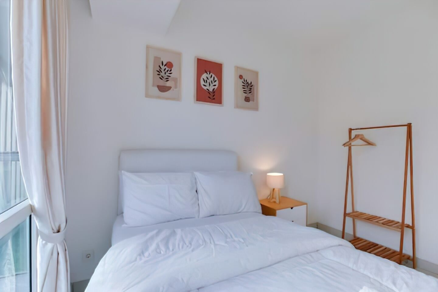 A bedroom with a bed, a bedside table with a lamp, and a wooden drying rack.