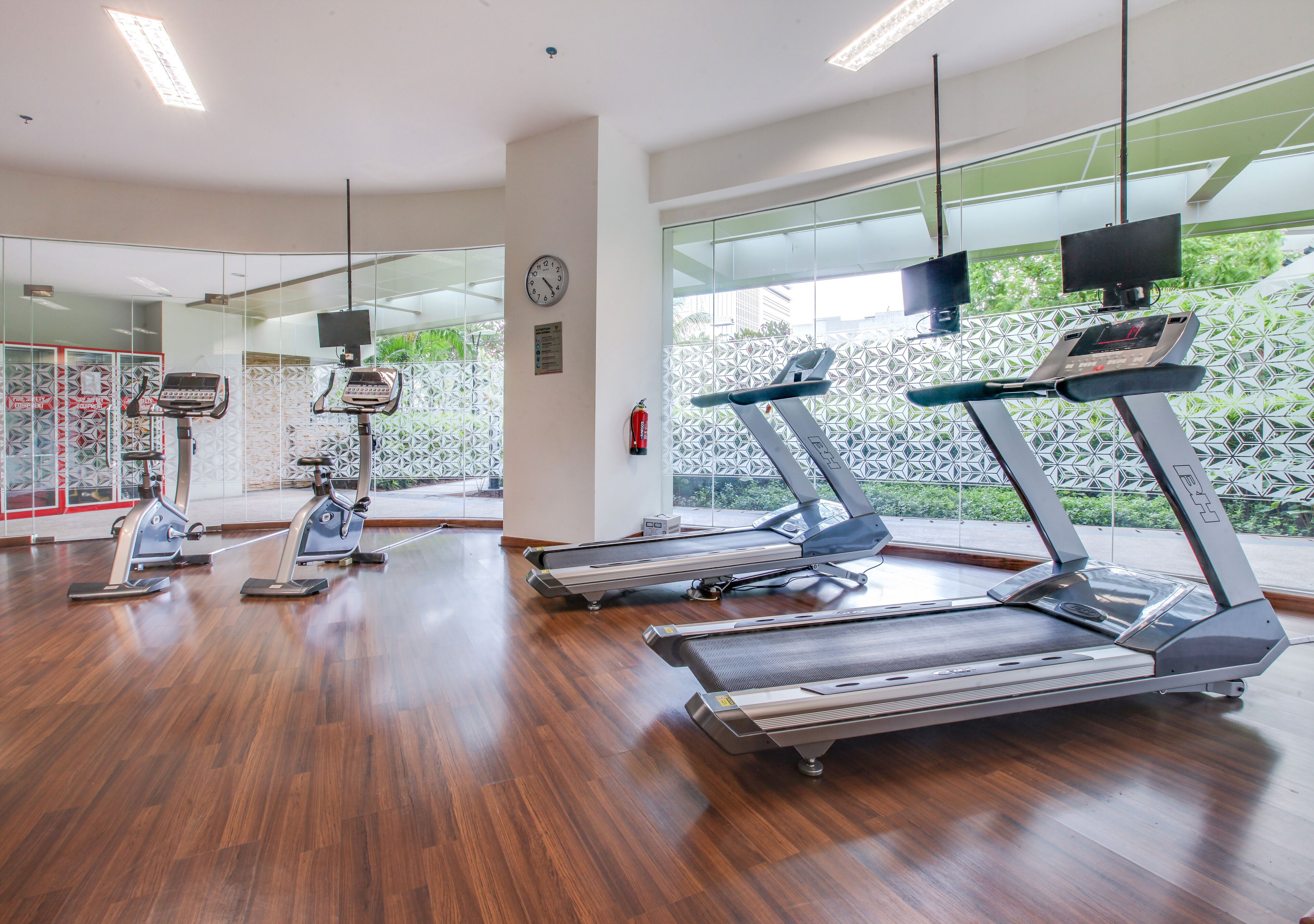 A gym with treadmills, stationary bikes, and a mirrored wall.