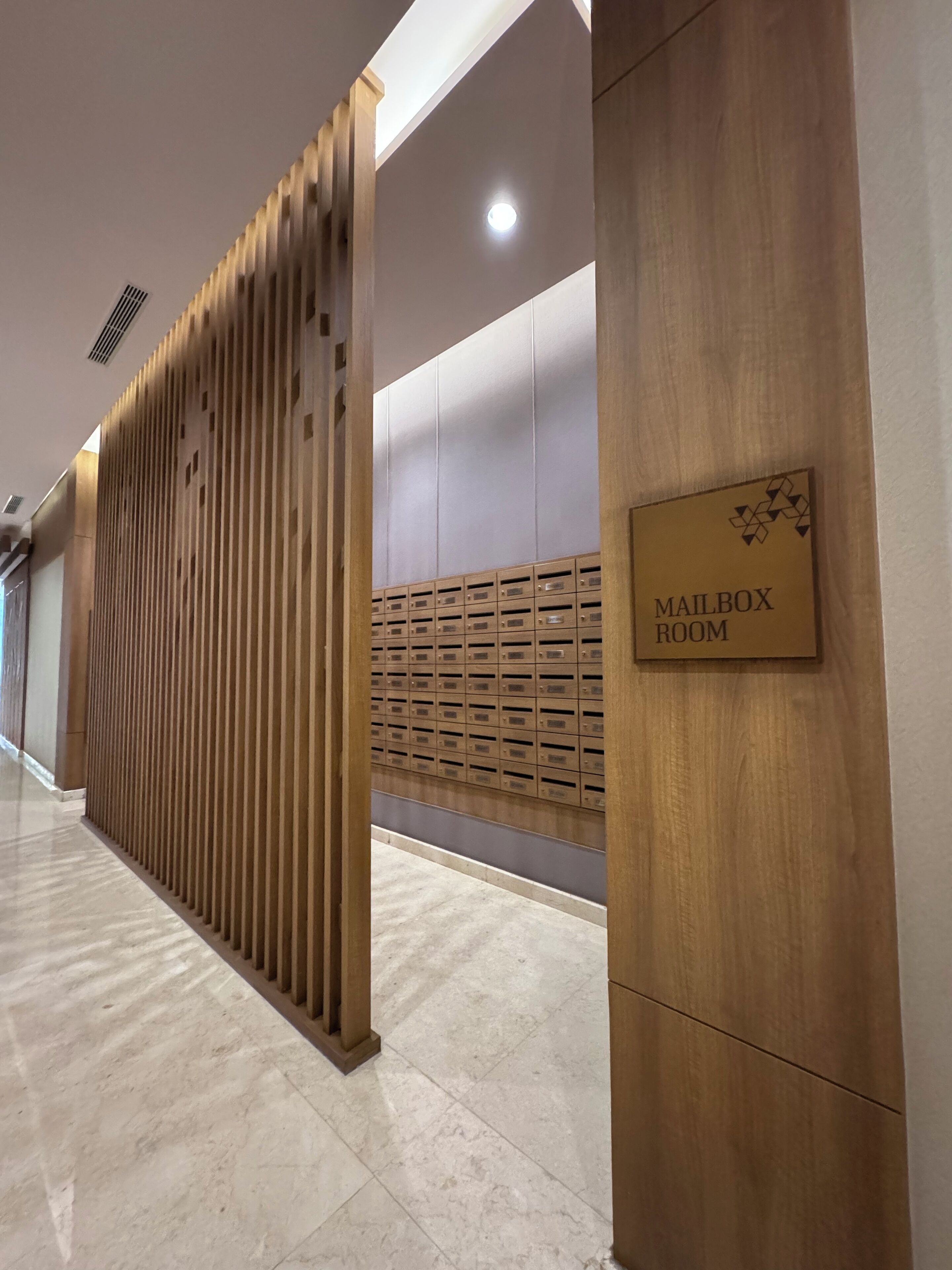 A hallway with a wooden partition, a mailbox room sign, and a wall with mailboxes.