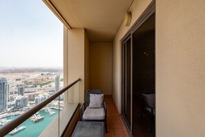 A balcony with a view of a marina and cityscape, a chair with a cushion, and a table.