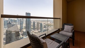 Ein Balkon mit Blick auf die Stadt, ein Korbstuhl, ein kleiner Tisch und hohe Gebäude im Hintergrund.
