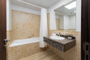 A bathroom with a bathtub, a sink, and a mirror.