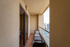 A balcony with a view of the city, a table, and two chairs.