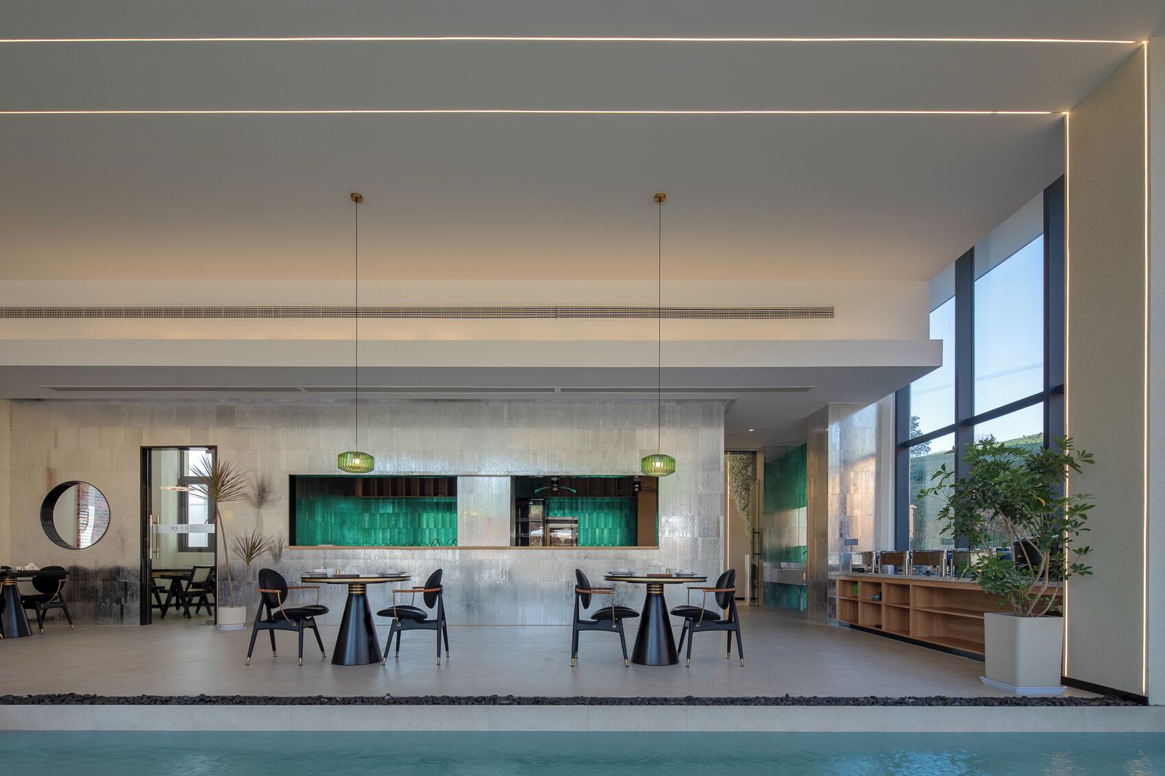 Un área de piscina interior moderna con asientos y un ventanal grande.