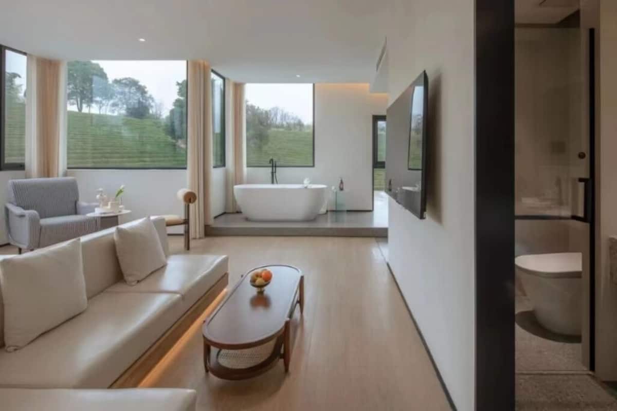 A modern bathroom with a freestanding bathtub, a large mirror, and a toilet.