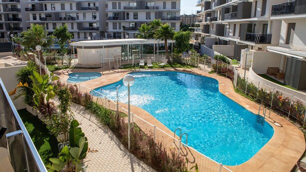 Une piscine dont le centre est plus profond que le reste, entourée d’une clôture et agrémentée de diverses plantes.